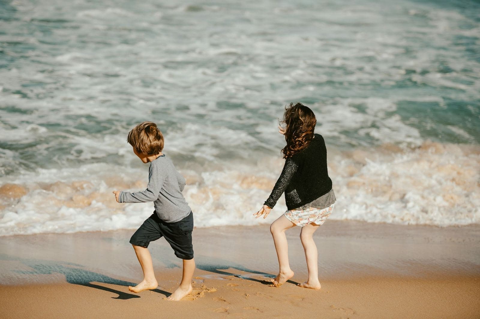Two children playing at the edge of the surf