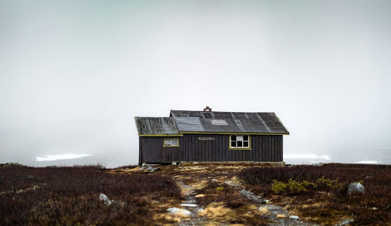 A lone wooden cabin on a misty hillside