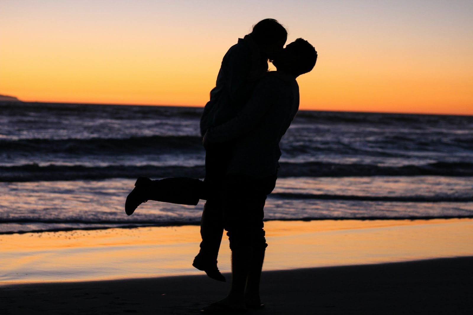 A couple silhouetted on the beach at sunset